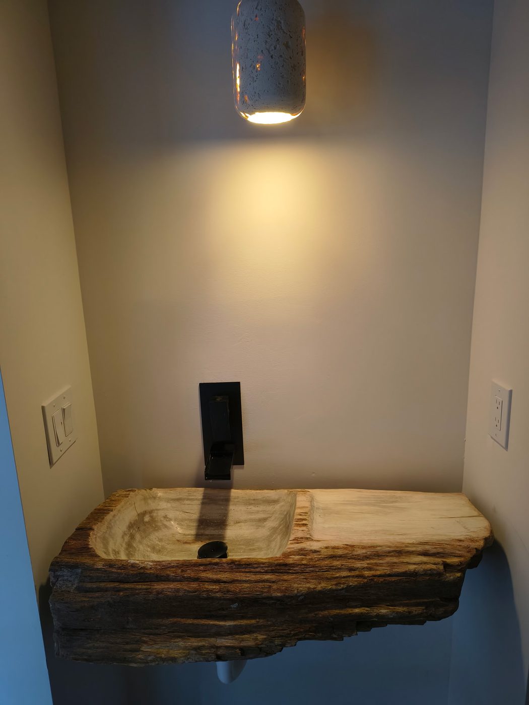 Custom petrified wood vessel sink with black wall-mount faucet